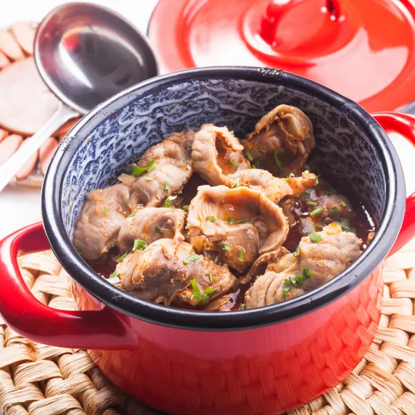 Photo d'une cocotte rouge avec des gésiers de poulet mijotés avec sauce tomate